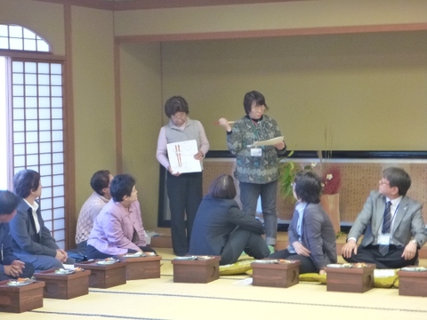 和室に集まり箱膳を前にして作法を学ぶ参加者たちの写真