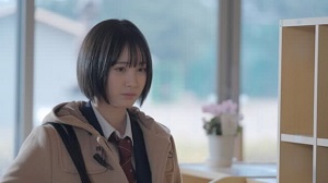 ベージュのコートを着た制服姿の女子学生の写真