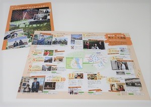千曲市ロケ地マップの表紙の上に、地図と多くの写真が掲載されているロケ地マップが開かれて置かれている写真