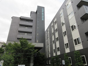 濃いグレーの外壁をした建物が二つ並んで立っている、ビジネスホテルの外観の写真