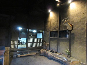 鹿の置物や木のベンチなどが並んでいる、建物内部の土間の写真