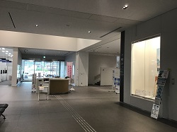 右手に照明で照らされた展示スペースがある、建物のホール部分を撮影した写真