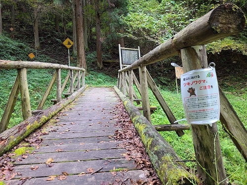 「登山におけるツキノワグマにご注意を」などと書かれた注意書きの掲示物が貼られた三滝へ向かう橋の写真