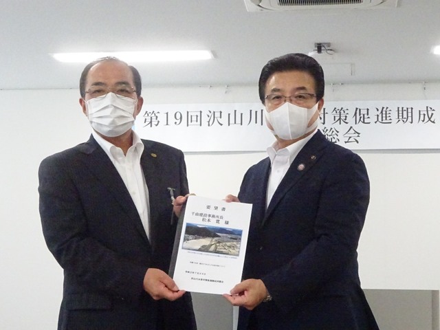 マスクをした市長と事務局長が並んで冊子をカメラに向けて立っている写真
