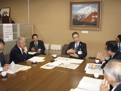 机をくっつけて着席し、建設部長や市長をはじめとする関係者一同が会議を行う写真