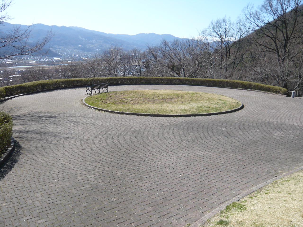 中心に円形の芝生がある、円形をした石畳の広場の写真