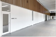 白い壁の上部に細い木の板が並んだ装飾が施されている、建物の内部の写真
