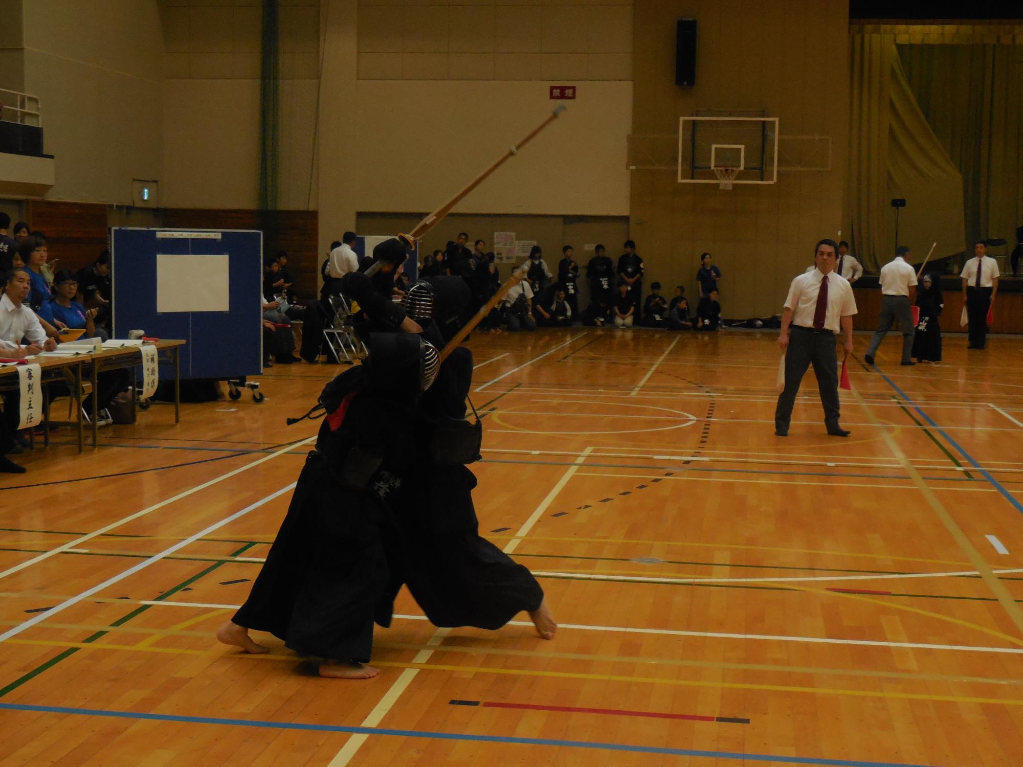 体育館で、竹刀を手にした子どもたちが剣道の試合を行っている写真