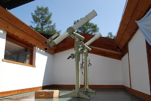 開いた屋根の下に天体望遠鏡が置かれている写真