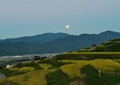 手前に姨捨の棚田、遠くには鏡台山、空には満月が登っている風景の写真