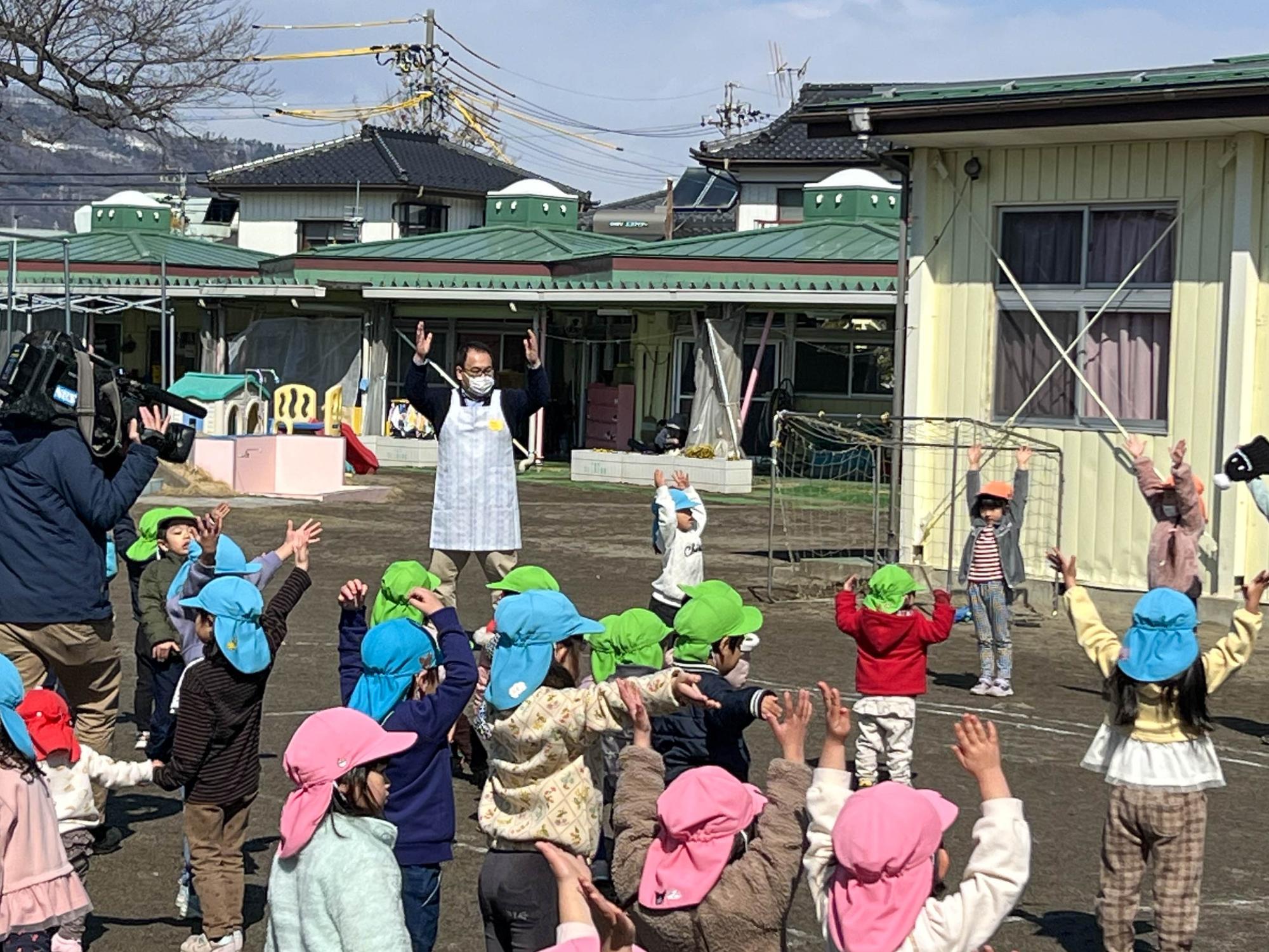 小川修一市長が園庭で子どもたちと体操をする様子