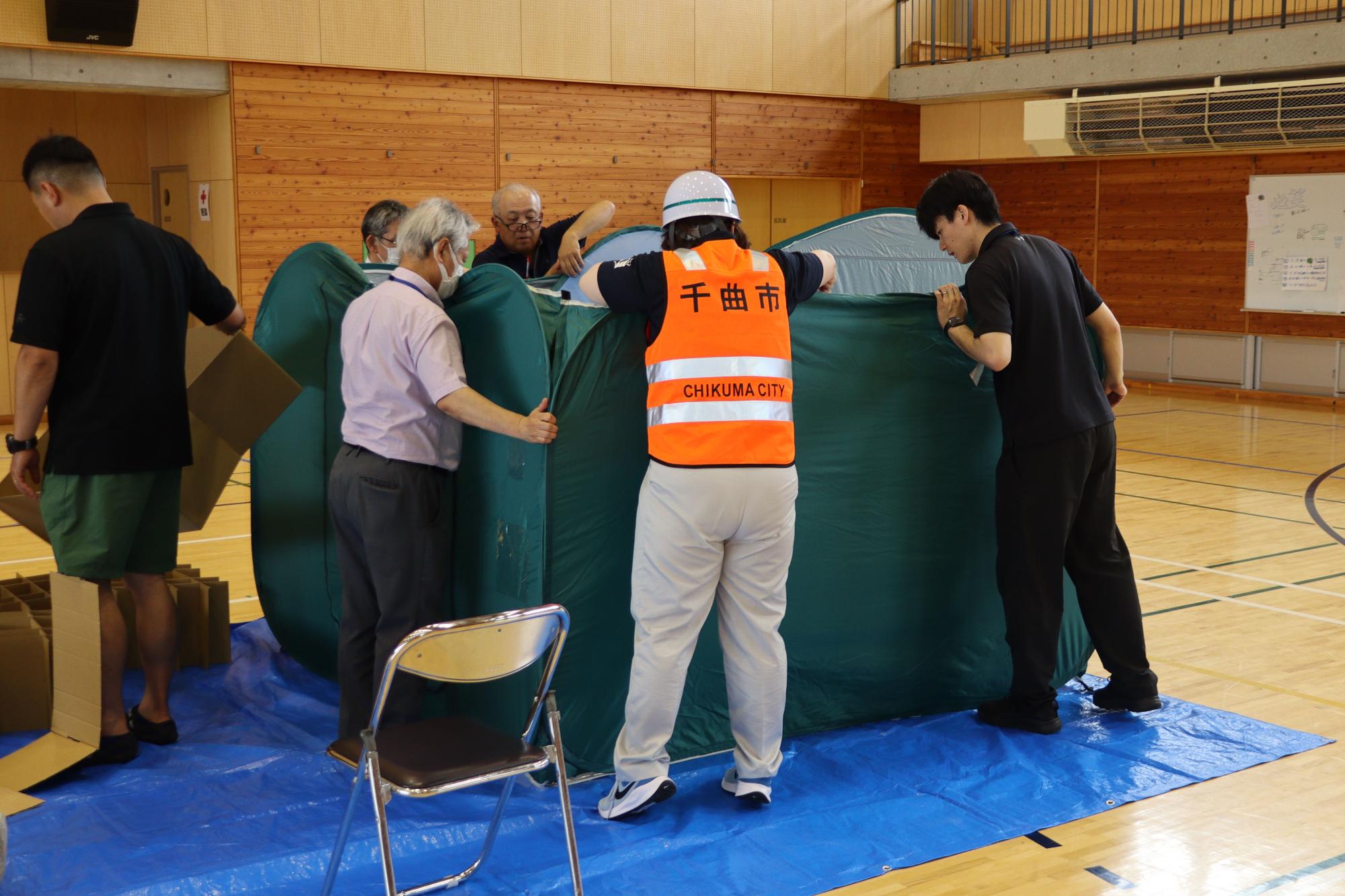 パーティションを組み立てる市職員と学校教職員