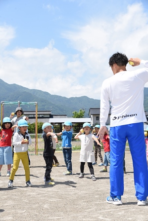 ボールを手に、指導する田中健太郎さんのポーズを真似て学習している園児達の写真