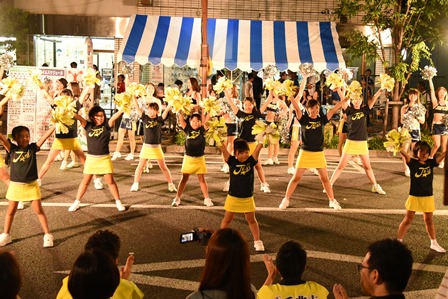 黄色いスカートを履いたチアガールたちが両手を挙げて踊っている写真