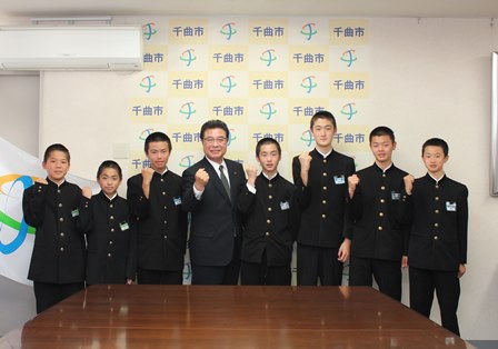横に並び、右手でガッツポーズをとる岡田市長と学生服姿の男子生徒達の写真