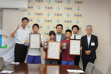 それぞれ額に入った賞状を持っている小学生3人と市長と職員2名の写真