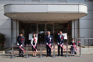 建物入口に並んで立ち、オープンセレモニーを行う市長らの写真