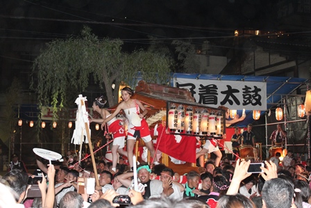 神輿の上に女性数人が乗り夏祭りが盛り上がっている写真