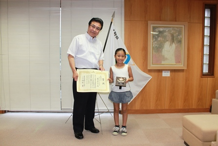 市長と塚田さんが表彰状と記念の楯を手に並んで記念撮影をしている写真