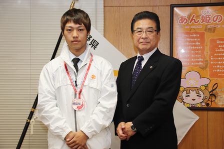 首からメダルを下げた亘敦司さんと岡田市長が並んで立っている写真