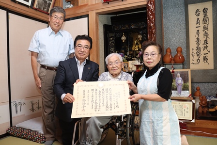 表彰状を受け取った宮坂とよ子さんご家族と市長が記念撮影をしている写真