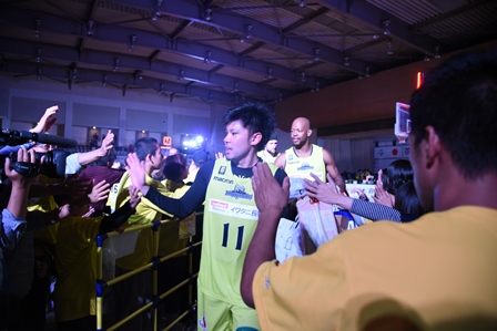観客の人とハイタッチしながら歩くバスケットボール選手の写真