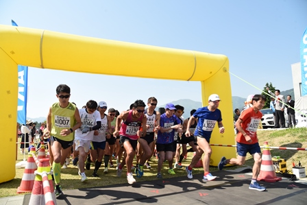 黄色いバルーンのスタート地点でハーフマラソンのスタートをきる選手たちの写真