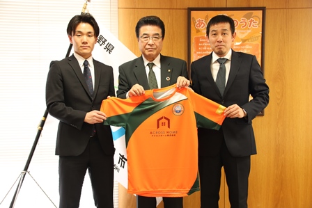 サッカークラブのキャプテンと監督が市長と一緒にユニフォームを持っている記念写真