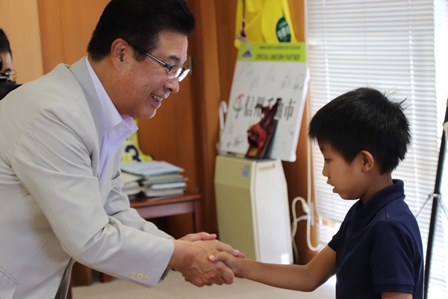 笑顔の市長と握手をしている小学生の男の子の写真