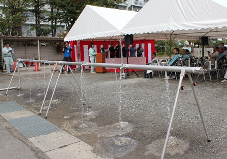 イベント用テントが並ぶ屋外で水を出している給水用の蛇口の写真