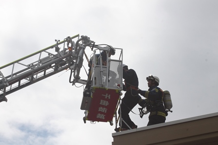 消防団員と市民が高所で高所避難訓練を行っている写真
