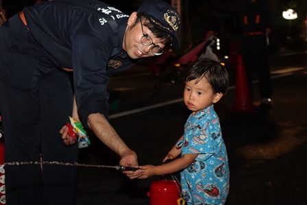 小さな子供に消火器の使い方を指導している消防団員の写真