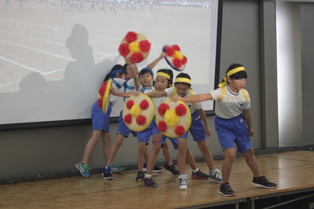 運動着を着た小学生6人が文化会館で花笠をつかったダンスを披露している写真