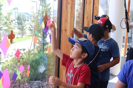 子供たちが窓に色紙を張り付けている写真