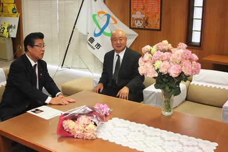 男性と市長がソファーに座って花瓶の花を見ながら懇談している写真