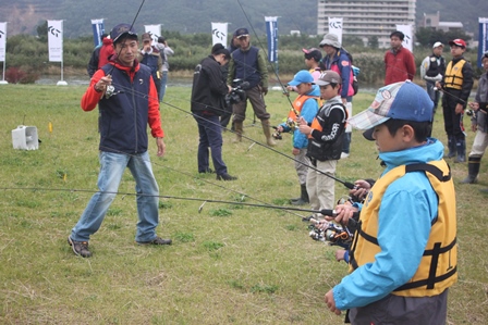 千曲川の河川付近で釣り具の練習をしている子どもたちと教えている大人たちの写真