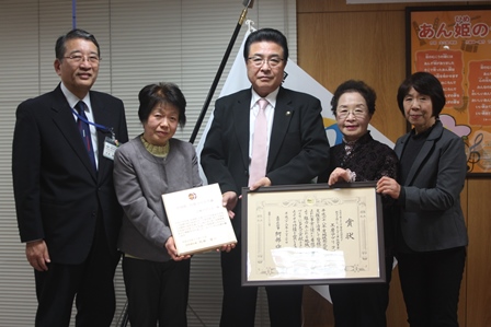 額縁に入った表彰状を手に、岡田市長らと並ぶ受賞者達の記念写真