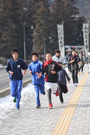 神社の前の道路を走っている男の子たちの写真