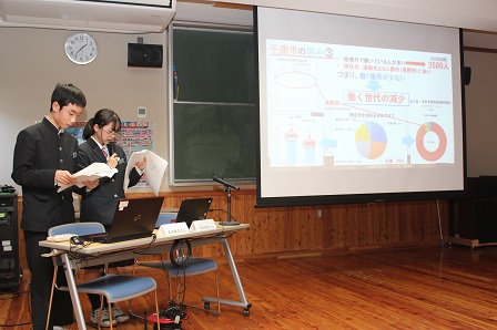 スクリーンに資料を映して説明をしている中村さんと松本くんの写真