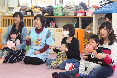 子育てセンターで職員と一緒に紙芝居を見ている子どもたちの写真