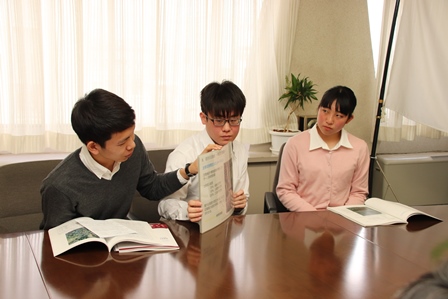 宮ノ内さん、宮島さん、山崎さんが椅子に座って資料を手に話している写真