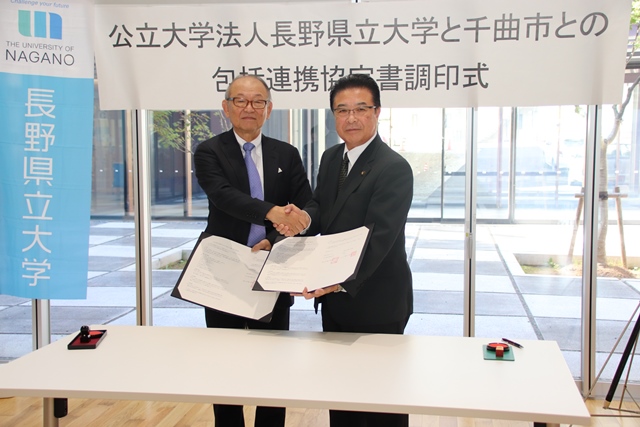 包括連携協定書調印式で市長と男性が握手をしている写真