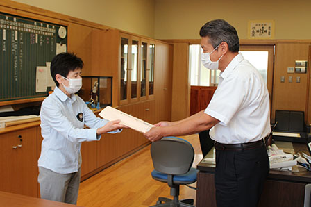 校長にチラシを手渡している高村会長の写真