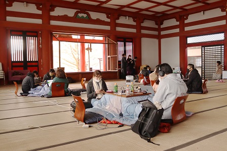 畳の敷かれた広々としたお寺の堂内でコタツに入ってワーケーションをしている参加者たちの写真