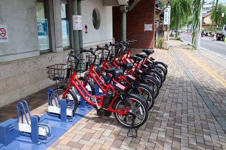 駐輪スペースに何台もの赤い自転車が止まっている写真