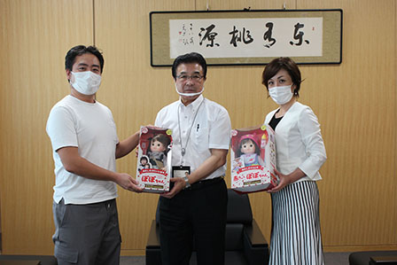 可愛らしい女の子の人形を手に持ち記念撮影をしている市長と実行委員長2名の写真
