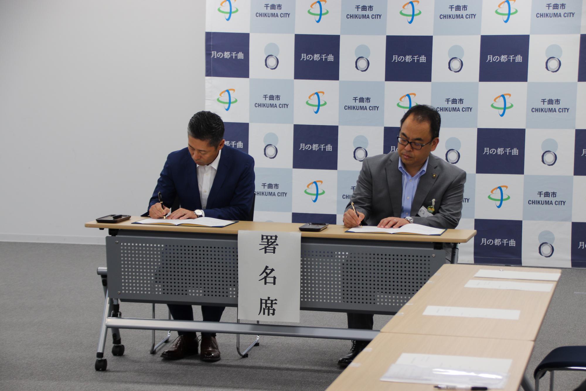 署名する小川市長と長野県司法書士会長野支部 高山正義支部長