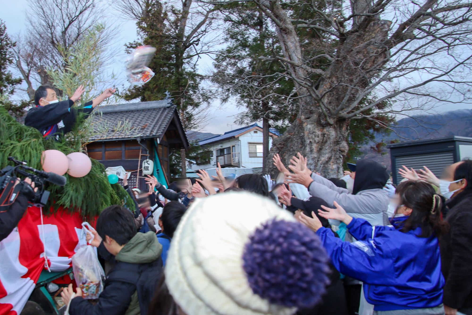 御供（ごく）まきの宝船に手を伸ばす集まった人たち