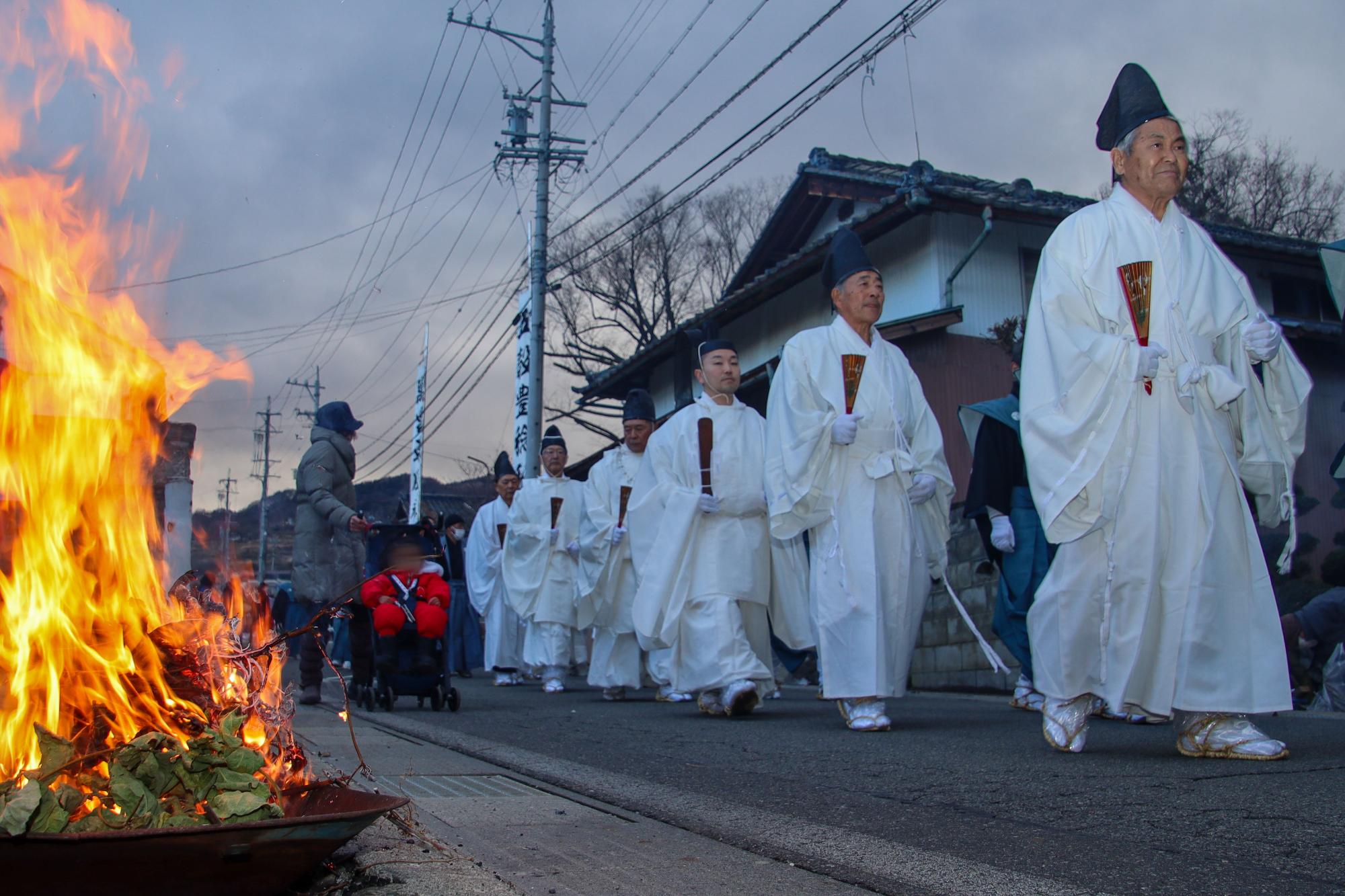 火が焚かれた沿道を歩く頭人（とうにん）