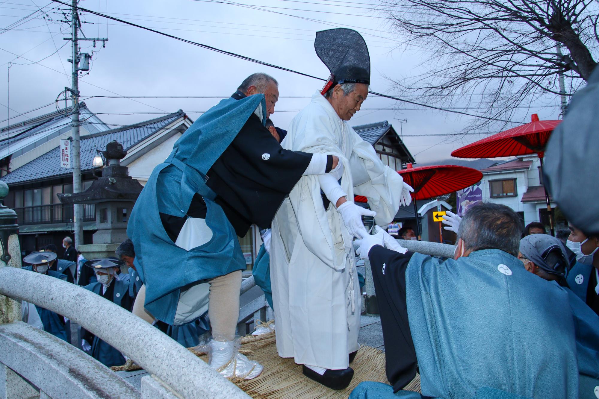 武水別神社（たけみずわけじんじゃ）にある橋を渡っている頭人（とうにん）